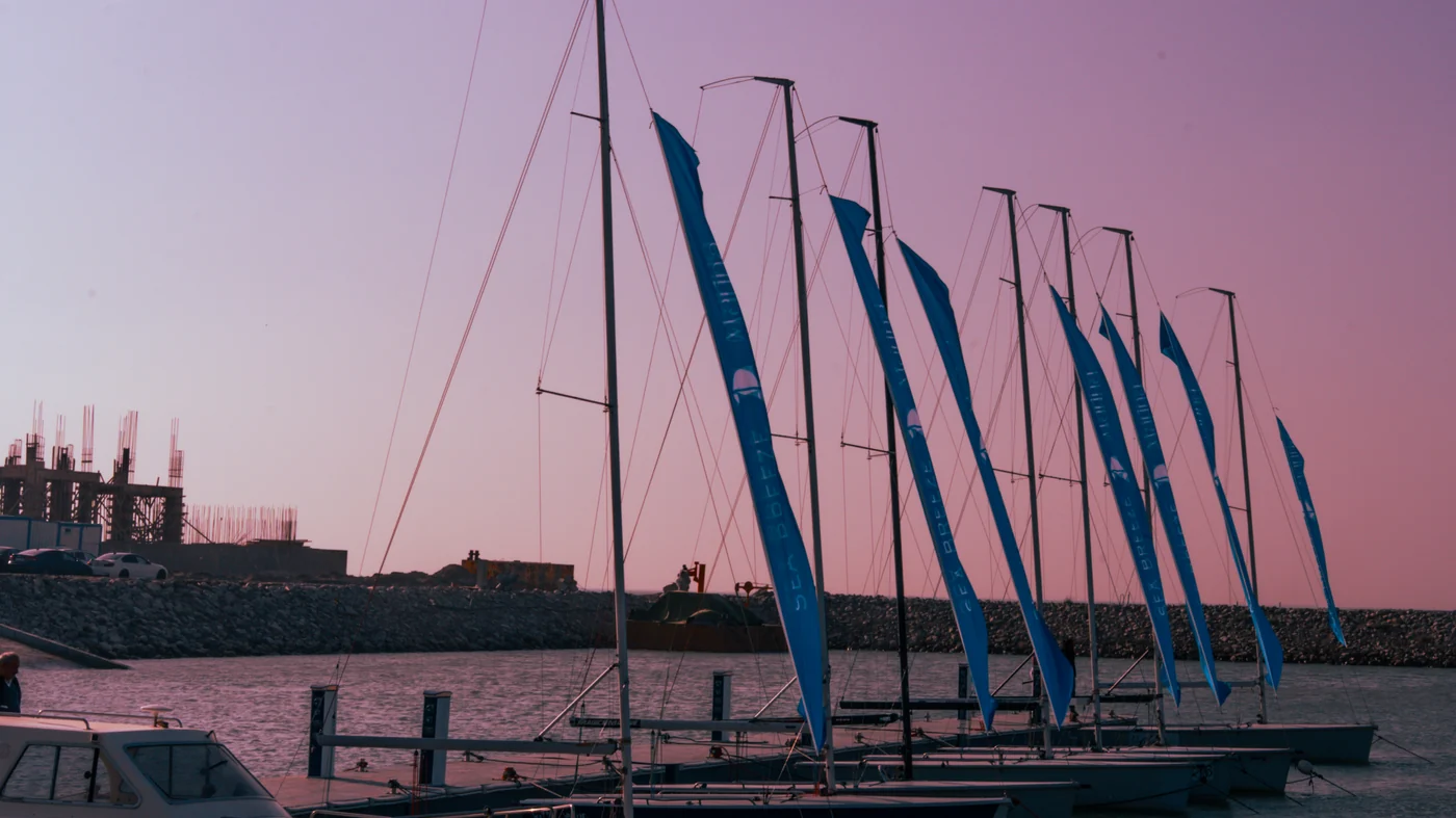 The masts and flags of the sailing school by the pontoon at sunset